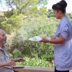 carer giving senior healthy food in residential home