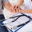 Doctor Holding Senior Patient's Hand Over Clipboard With Stethoscope